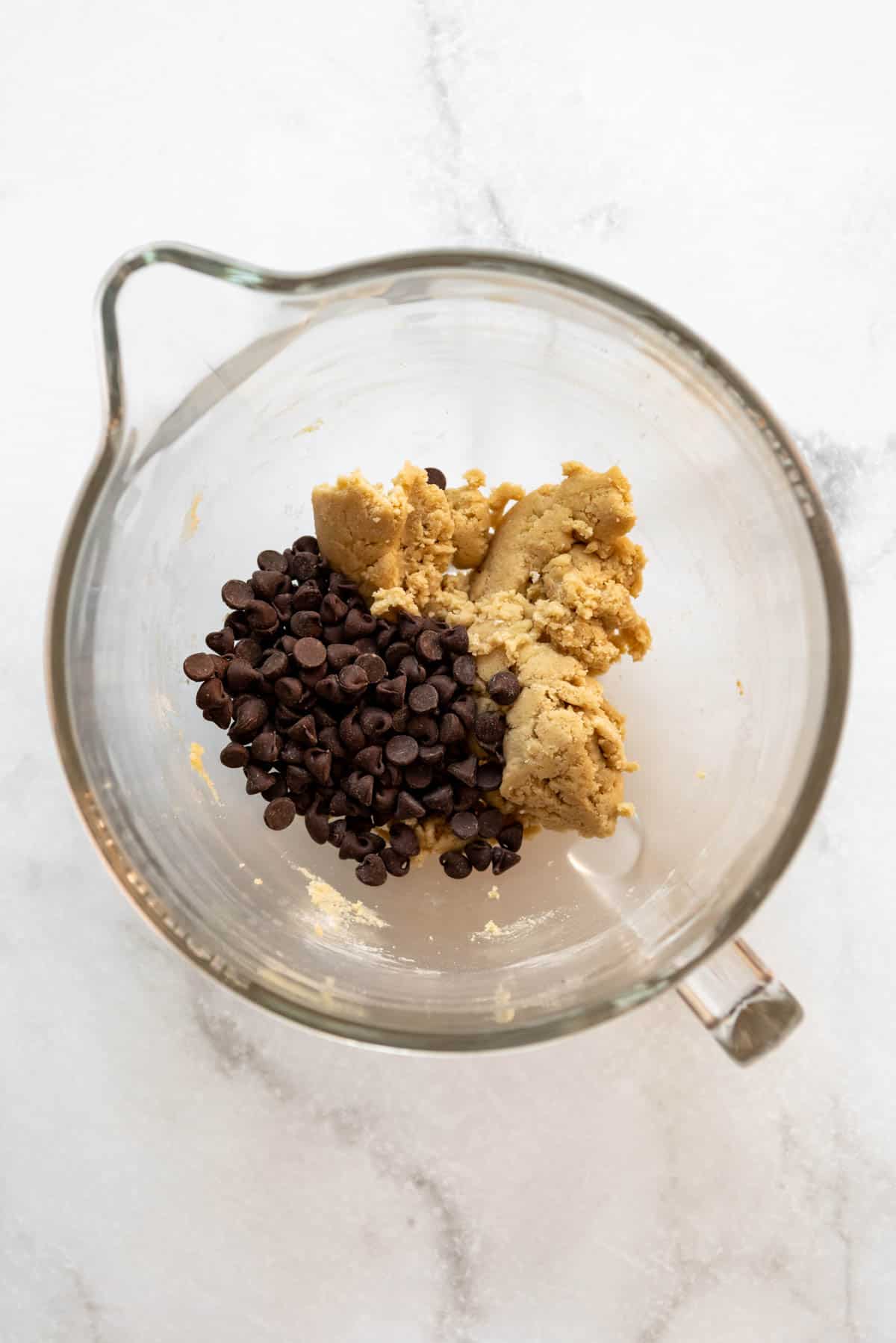 Adding semisweet chocolate chips to cookie dough.