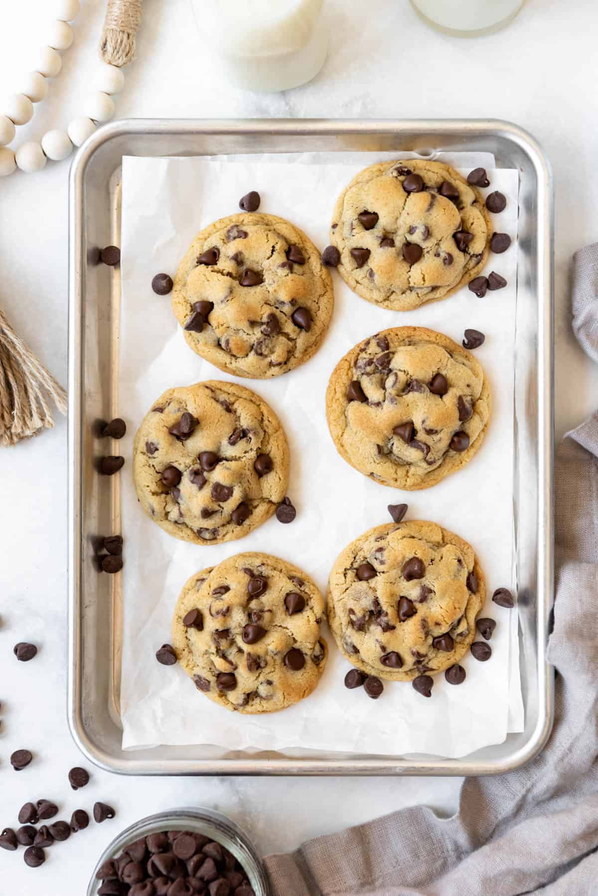 Six small batch chocolate chip cookies on a baking sheet.