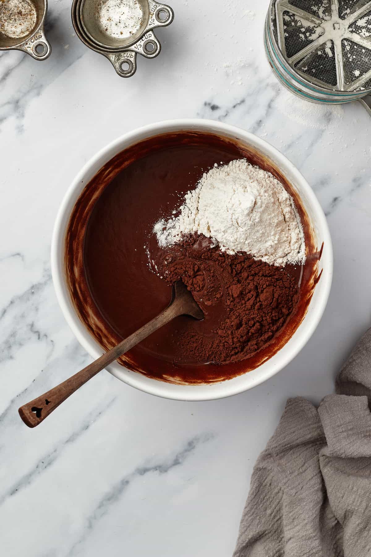In-progress brownie batter in a bowl with salt, flour and cocoa powder