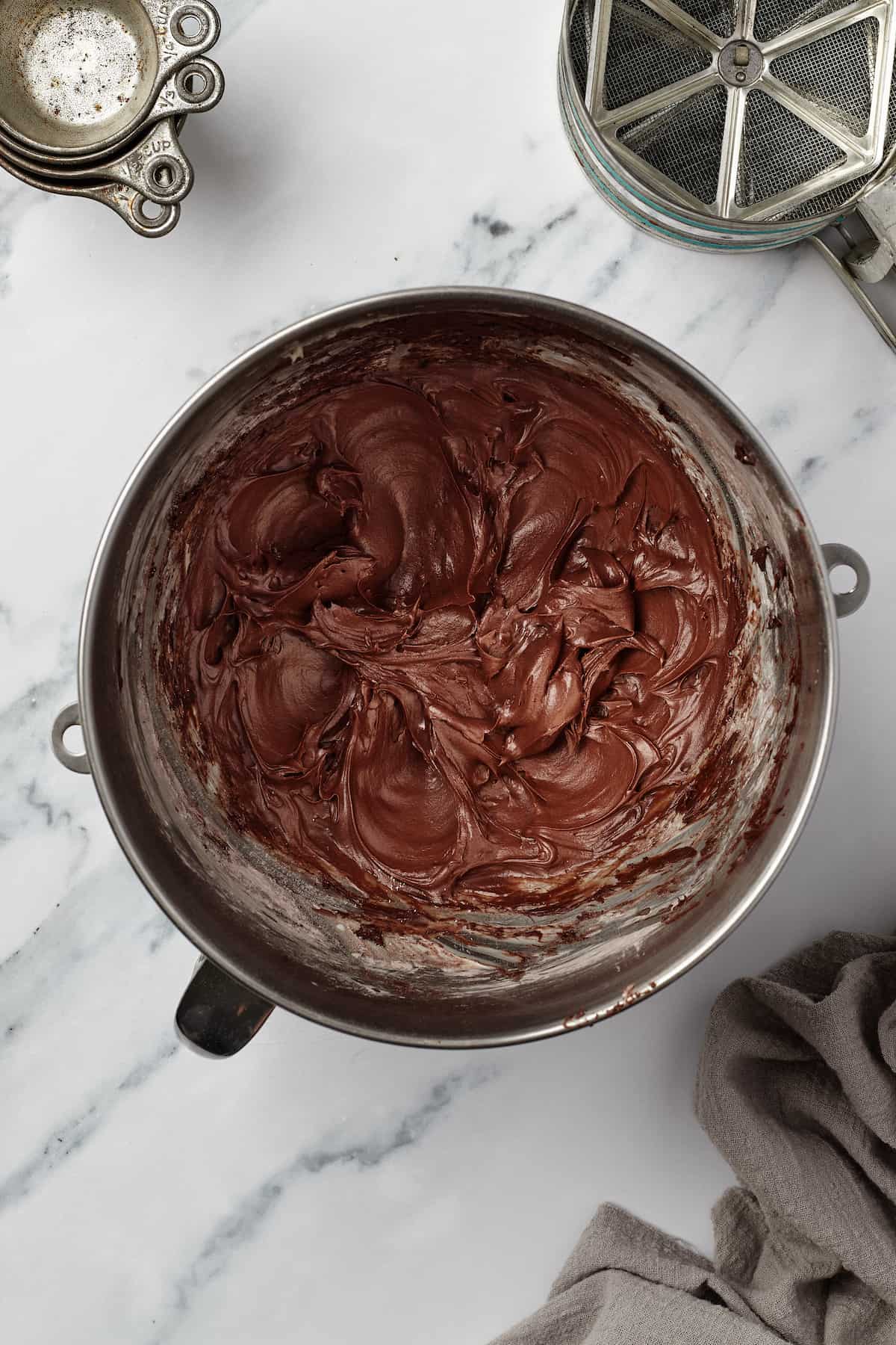 A metal mixing bowl full of homemade chocolate frosting