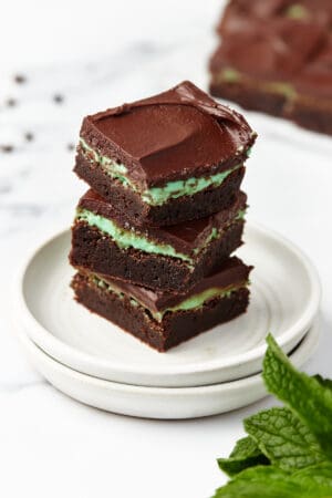 Three mint brownies stacked on top of a stack of two plates