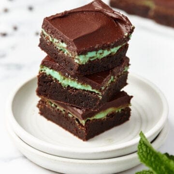 Three mint brownies stacked on top of a stack of two plates