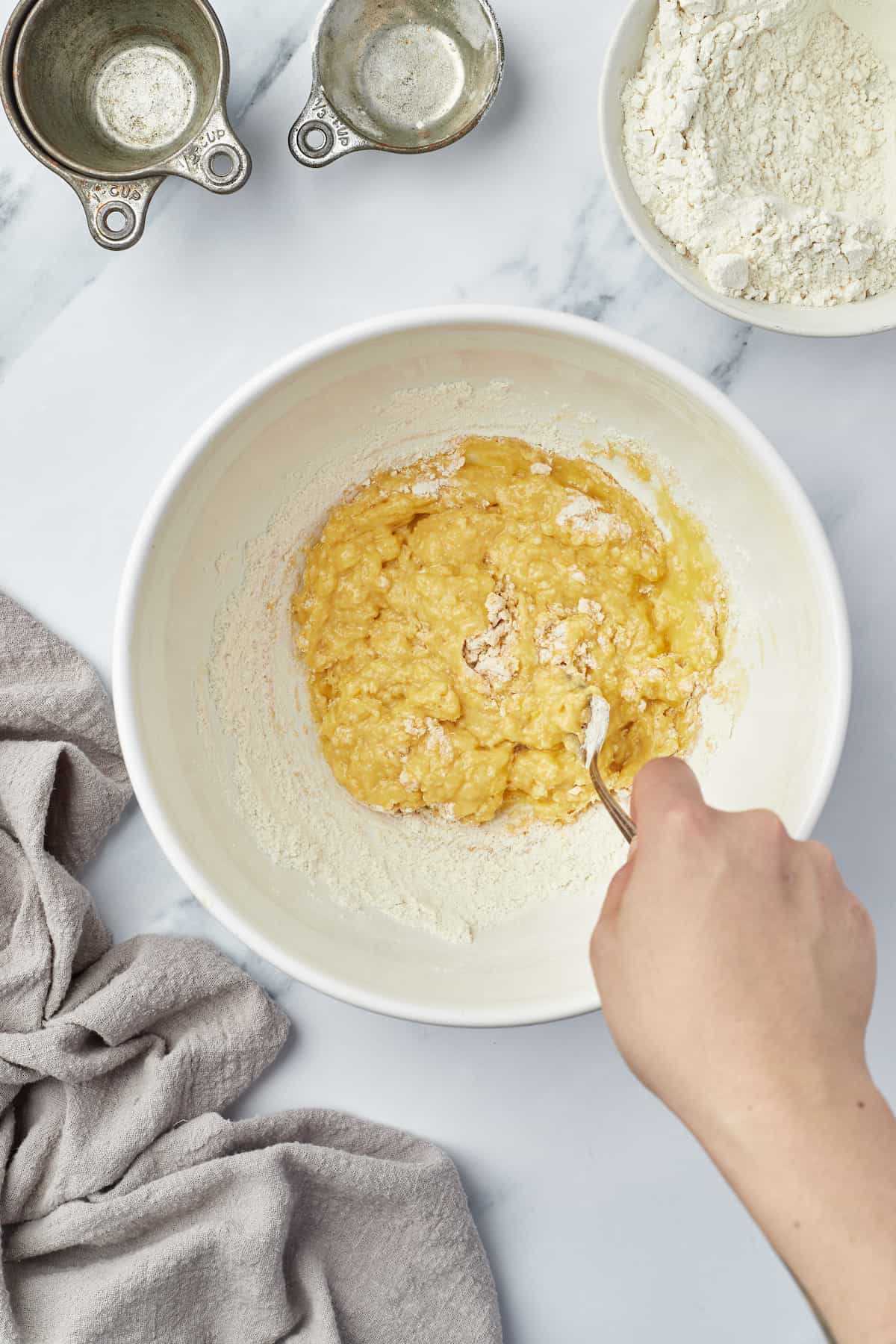 A mixing bowl full of egg noodle dough while the flour is being added