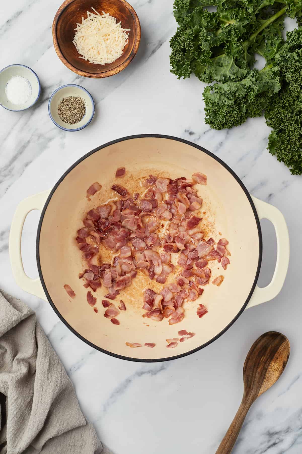 Cooked bacon bits inside of a large stockpot on a marble kitchen countertop