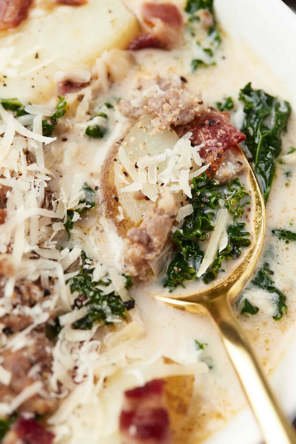 A close-up shot of a spoon scooping up a mouthful of Zuppa Toscana