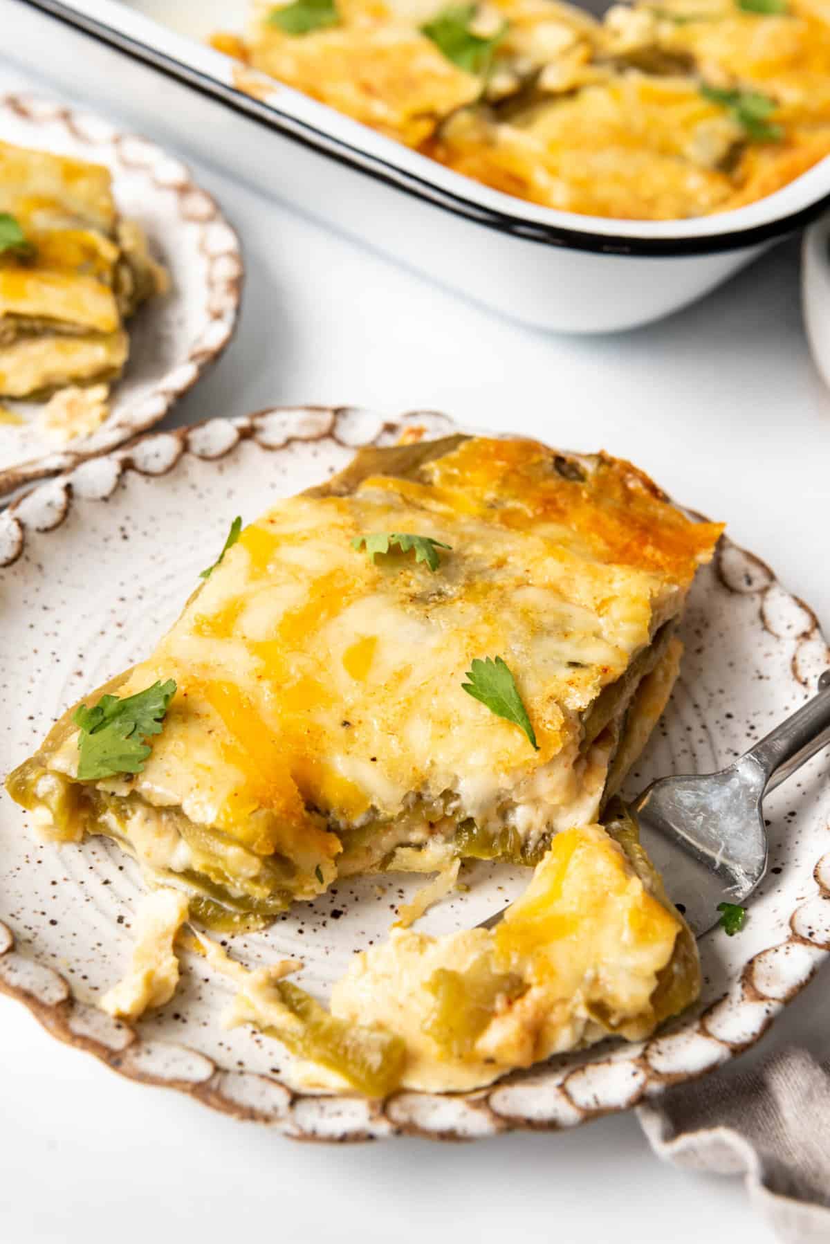 A slice of chile rellenos casserole on a plate with a bite taken out of it on a fork.