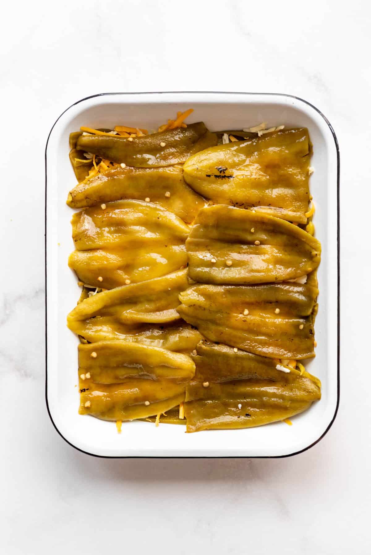 Repeating layers of green chiles in a casserole dish to make chile rellenos casserole.
