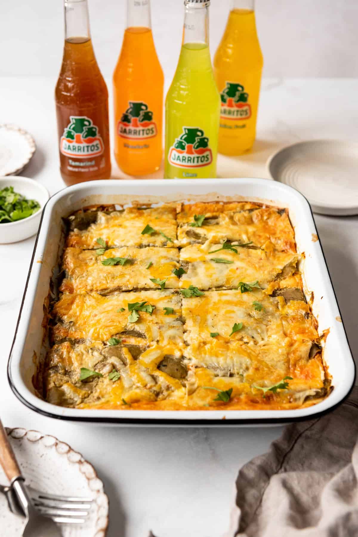 Easy chile rellenos casserole in a white baking dish in front of Mexican sodas.
