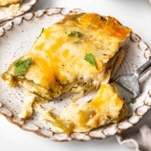 A slice of chile rellenos casserole on a plate with a bite taken out of it on a fork.