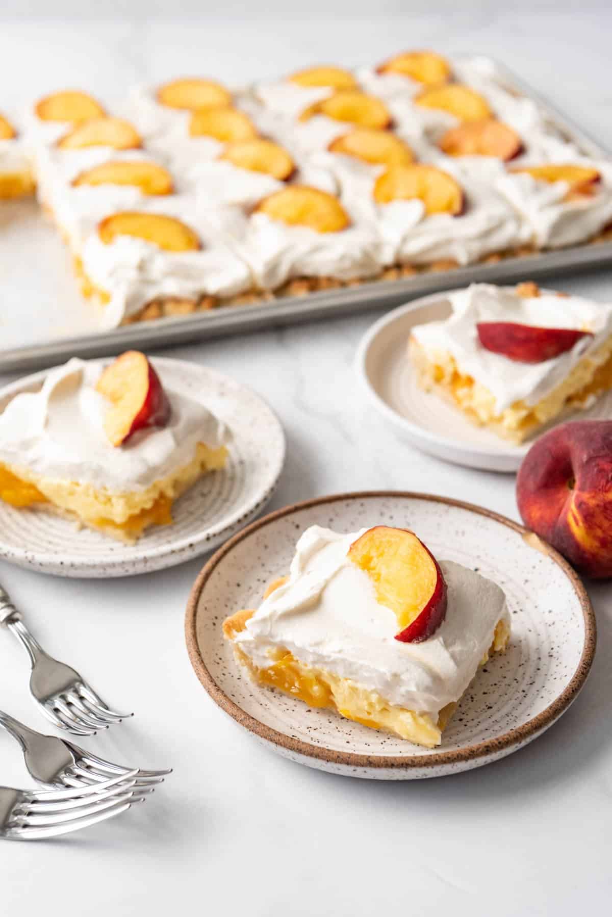 Peaches and cream pie decorated with fresh whipped cream and peach slices on plates.