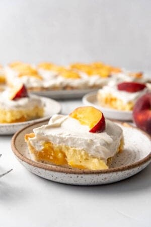 A slice of peaches and cream slab pie on an angle on a speckled plate.