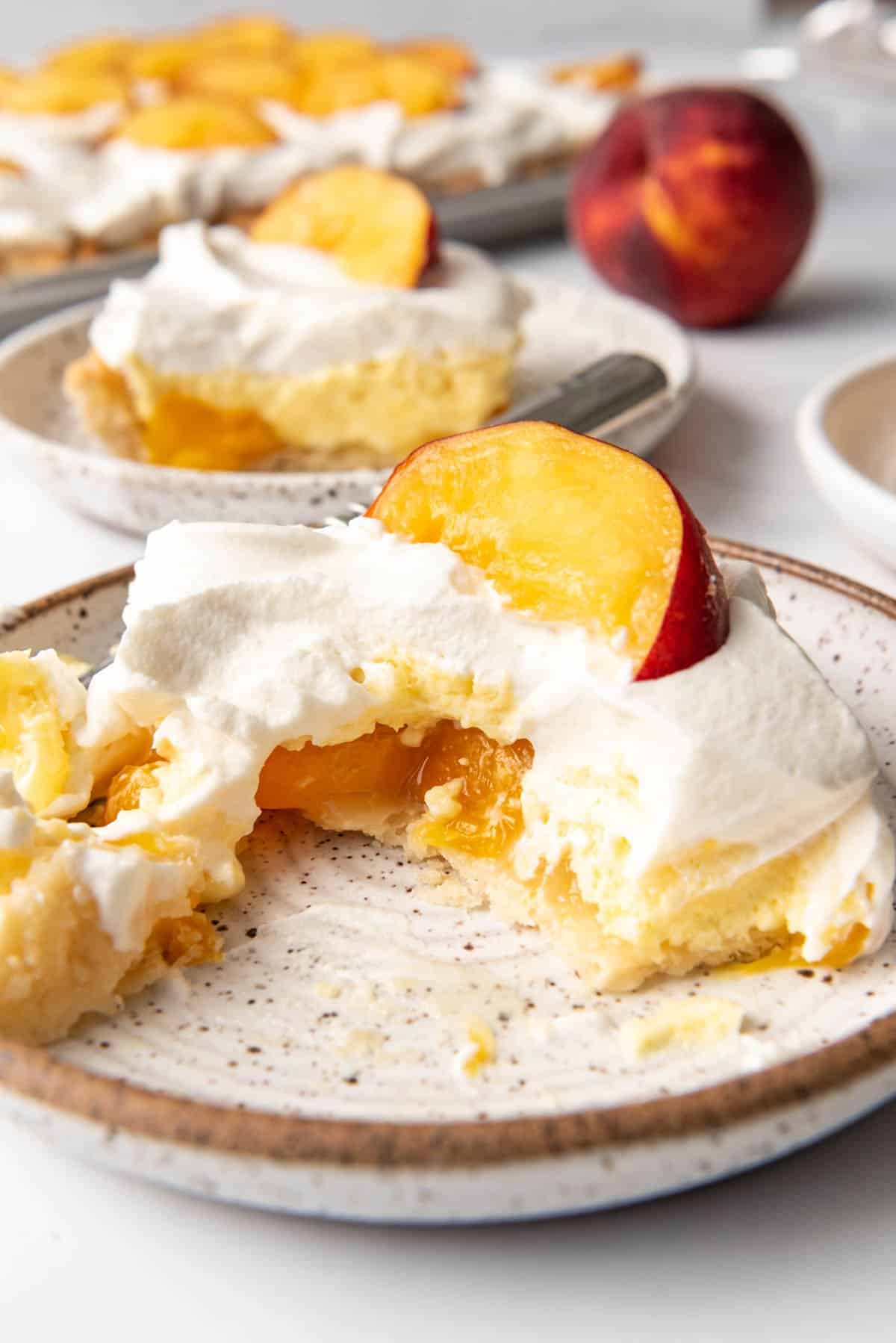 A piece of peaches and cream pie on a plate with a bite taken out of it.