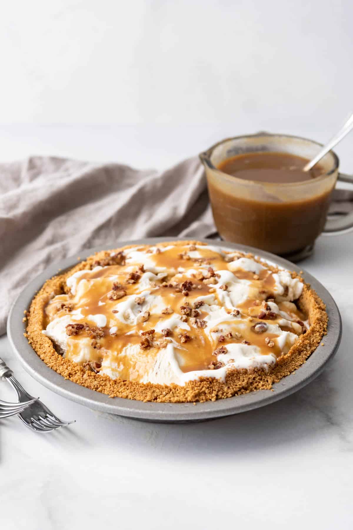 A butter pecan ice cream pie after being topped with butterscotch sauce.