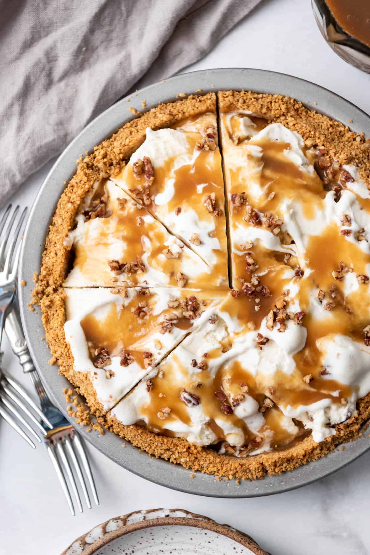 An overhead image of an ice cream pie with butter pecan ice cream and butterscotch sauce.