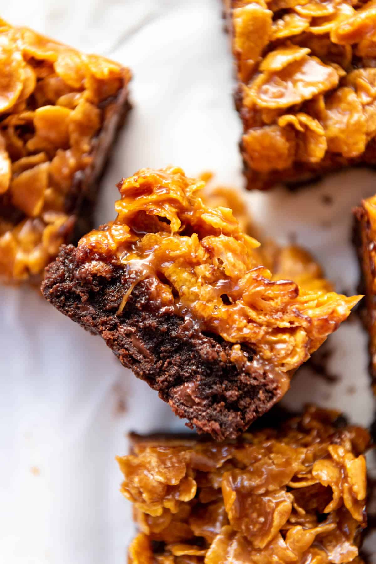 A fudgy brownie with a caramel cornflake layer on top laying on its side.