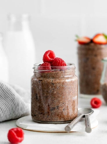 Chocolate chia seed pudding in a glass jar with raspberries on top.