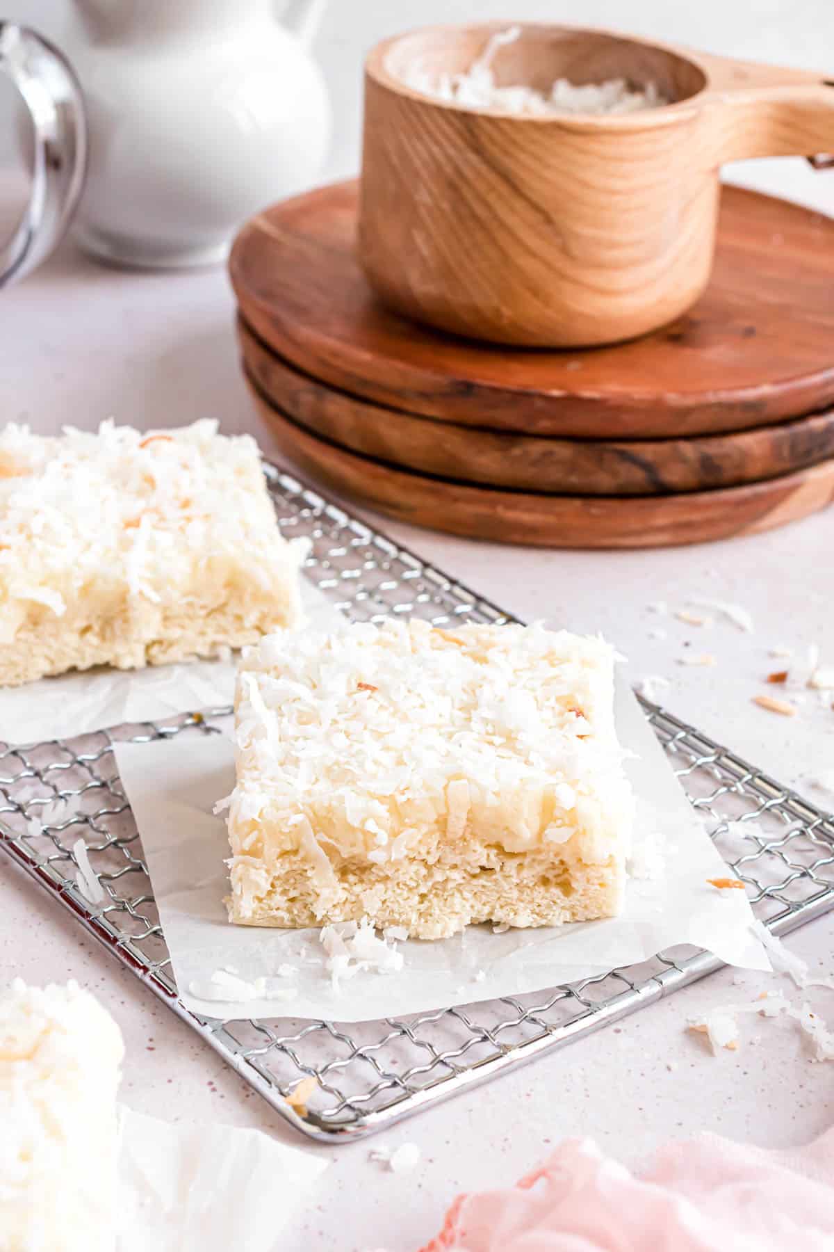 Frosted coconut sugar cookie bars on parchment paper squares.