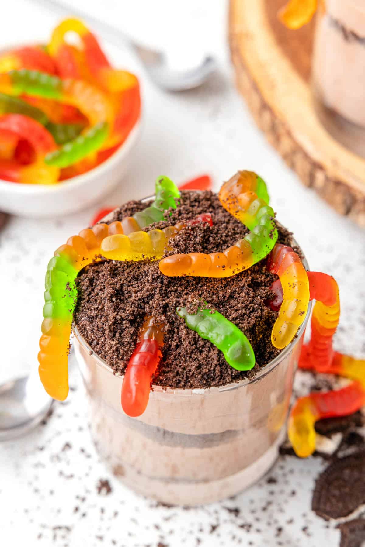 A chocolate pudding dirt cup dessert with gummy worms on top.