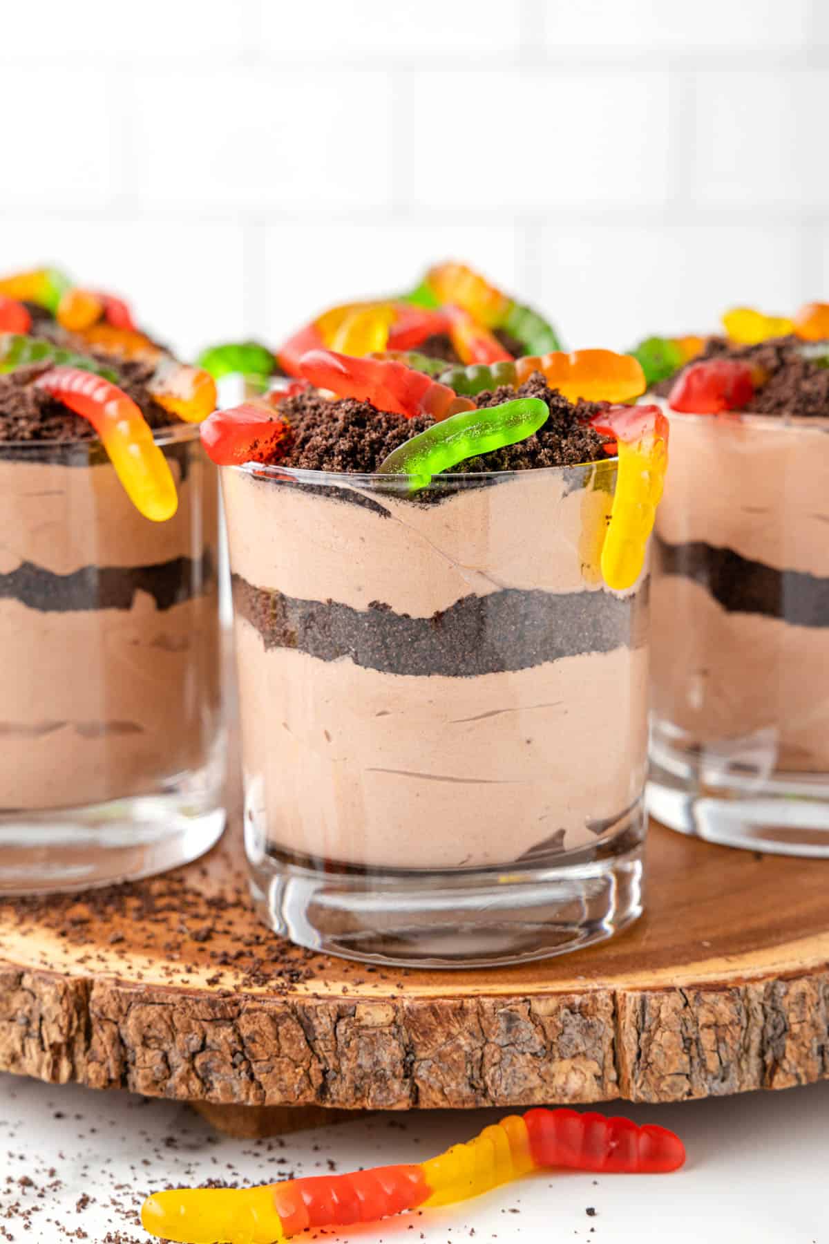 Dessert cups of dirt with gummy worms on top.