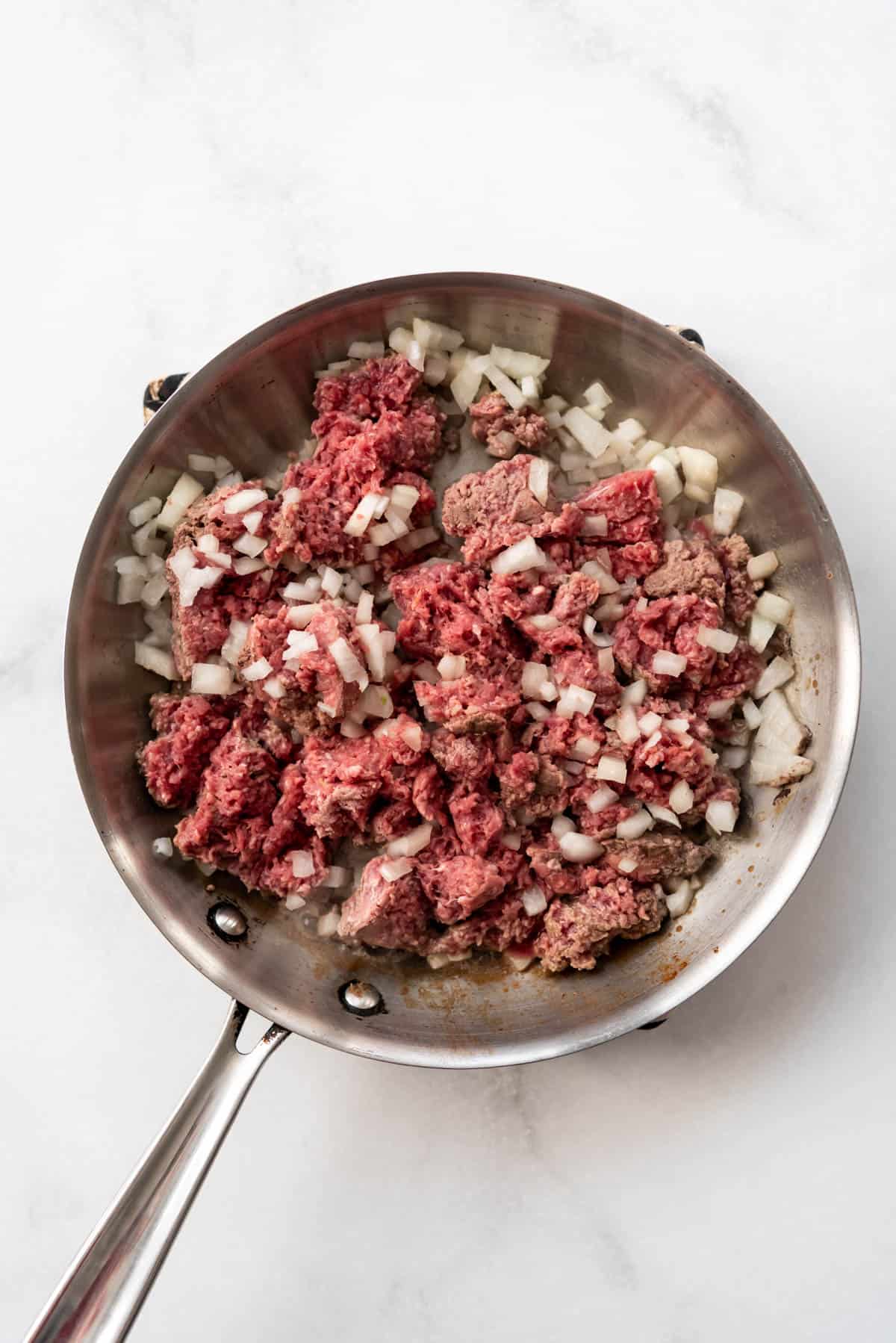 Browning ground beef in a pan with onions.