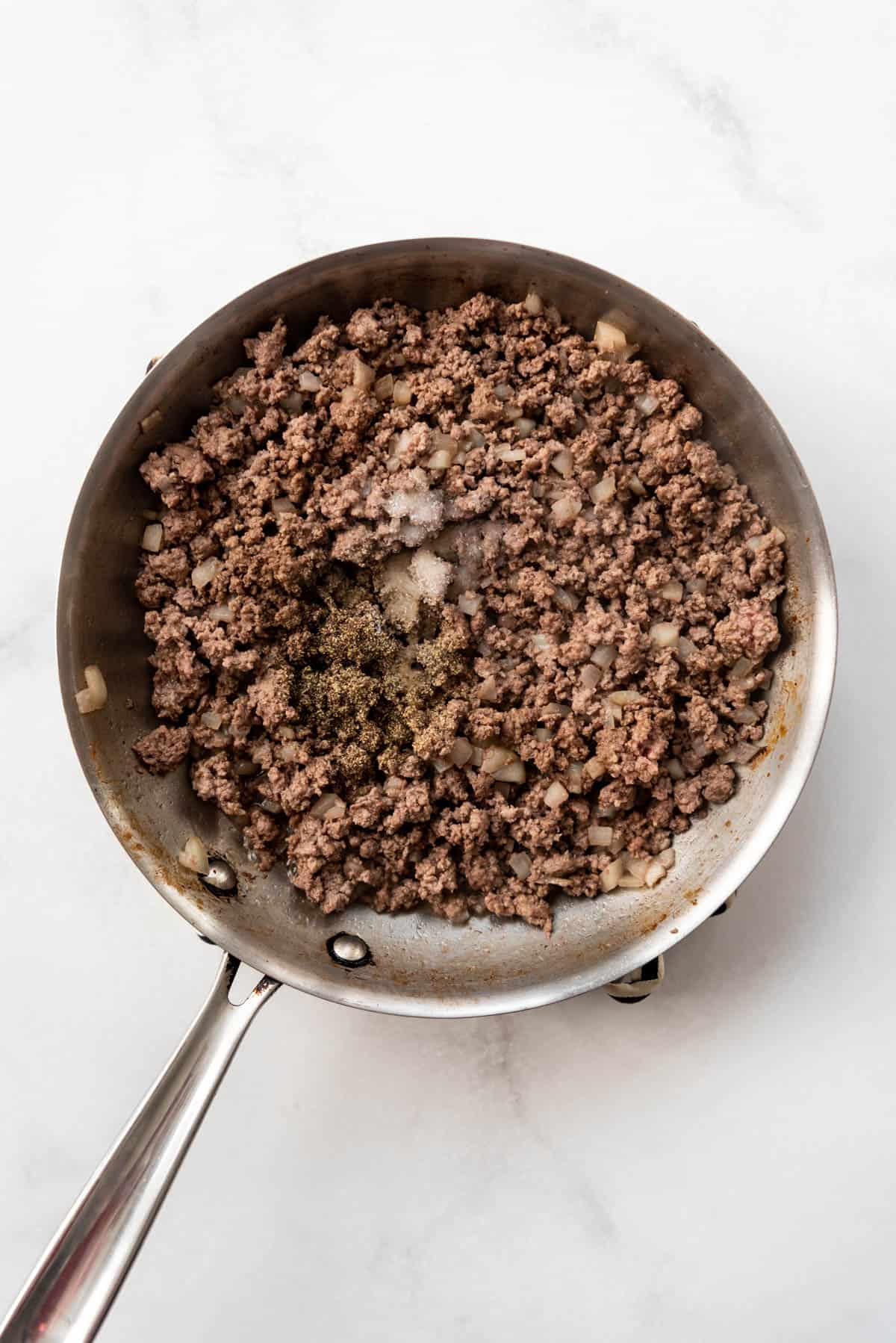Browned ground beef and onions in a pan.