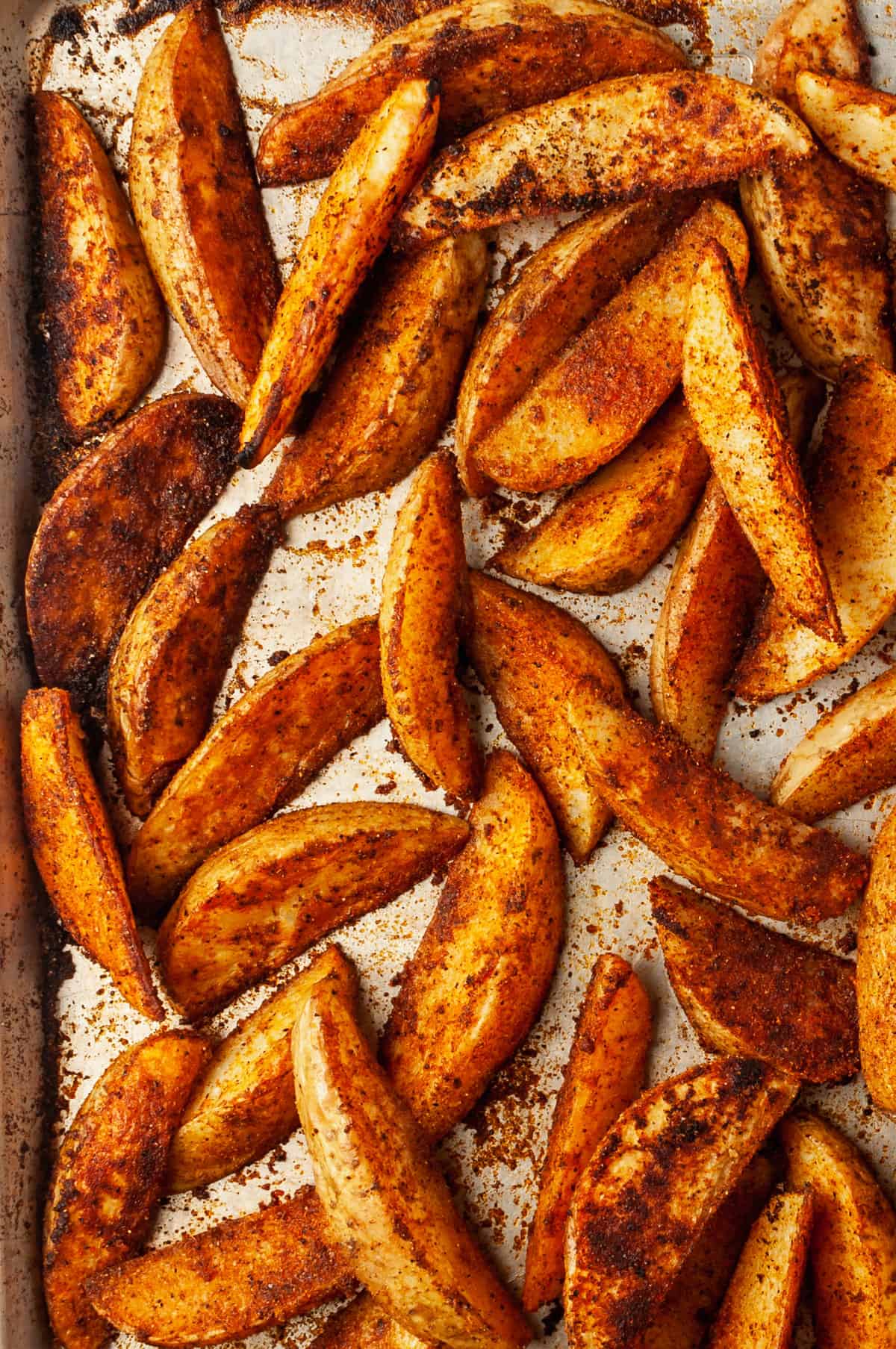 Overhead view of baked potato wedges on sheet pan
