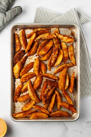 Overhead view of barbecue baked potato wedges on sheet pan