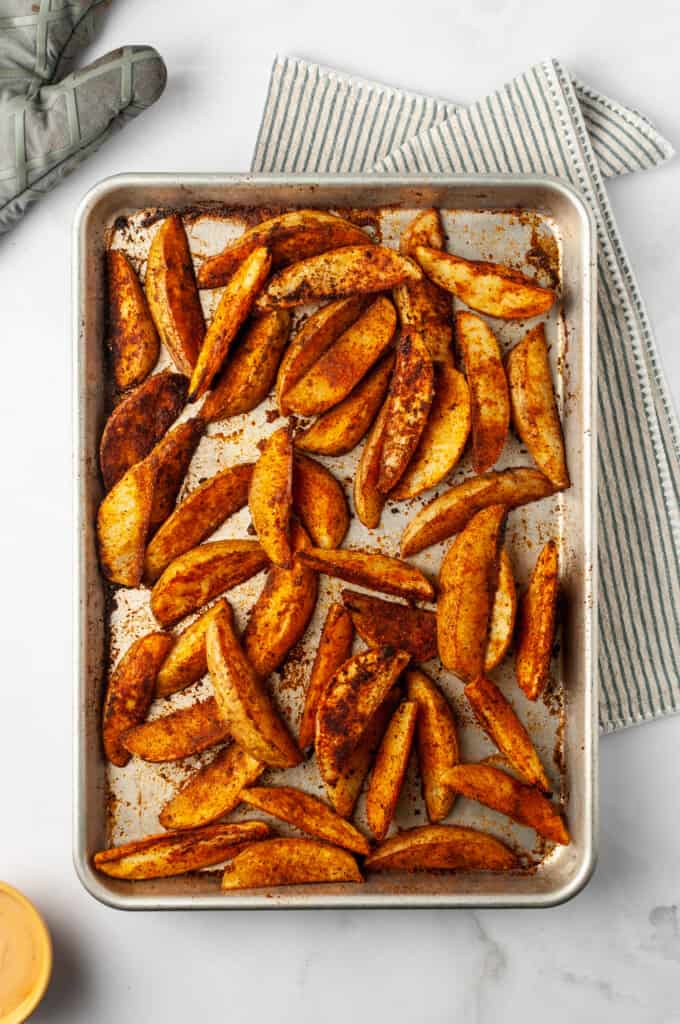 Overhead view of barbecue baked potato wedges on sheet pan
