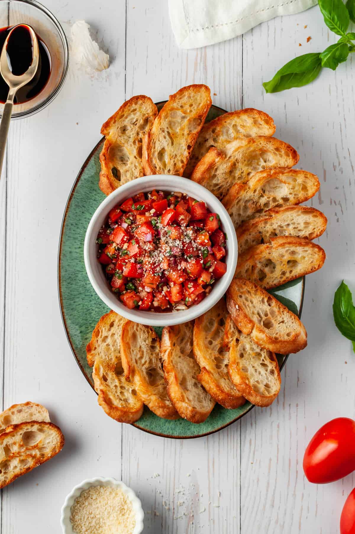 Sliced toasts and bowl of bruschetta topping on serving platter