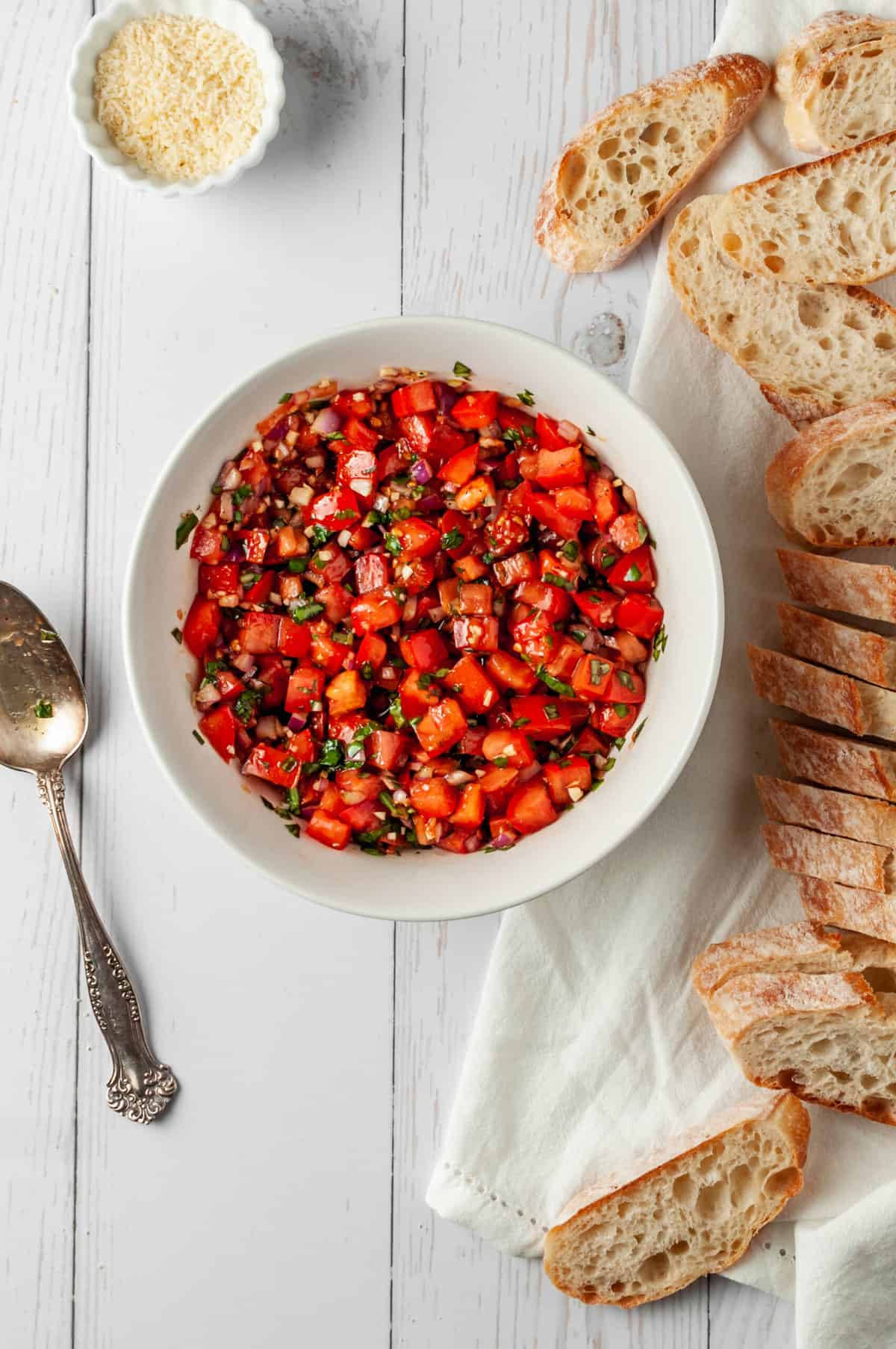 Bowl of tomato bruschetta topping with sliced baguette