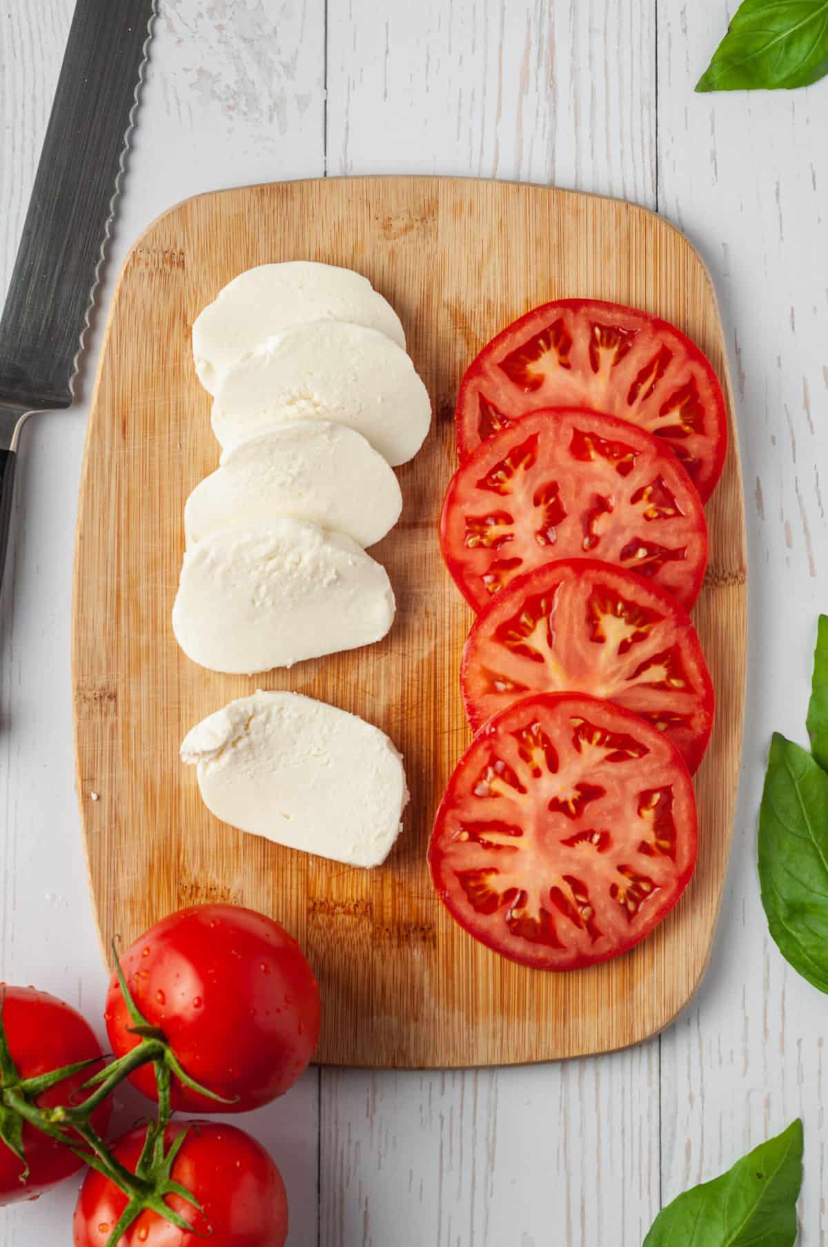 Slices of fresh mozzarella and tomatoes on cutting board
