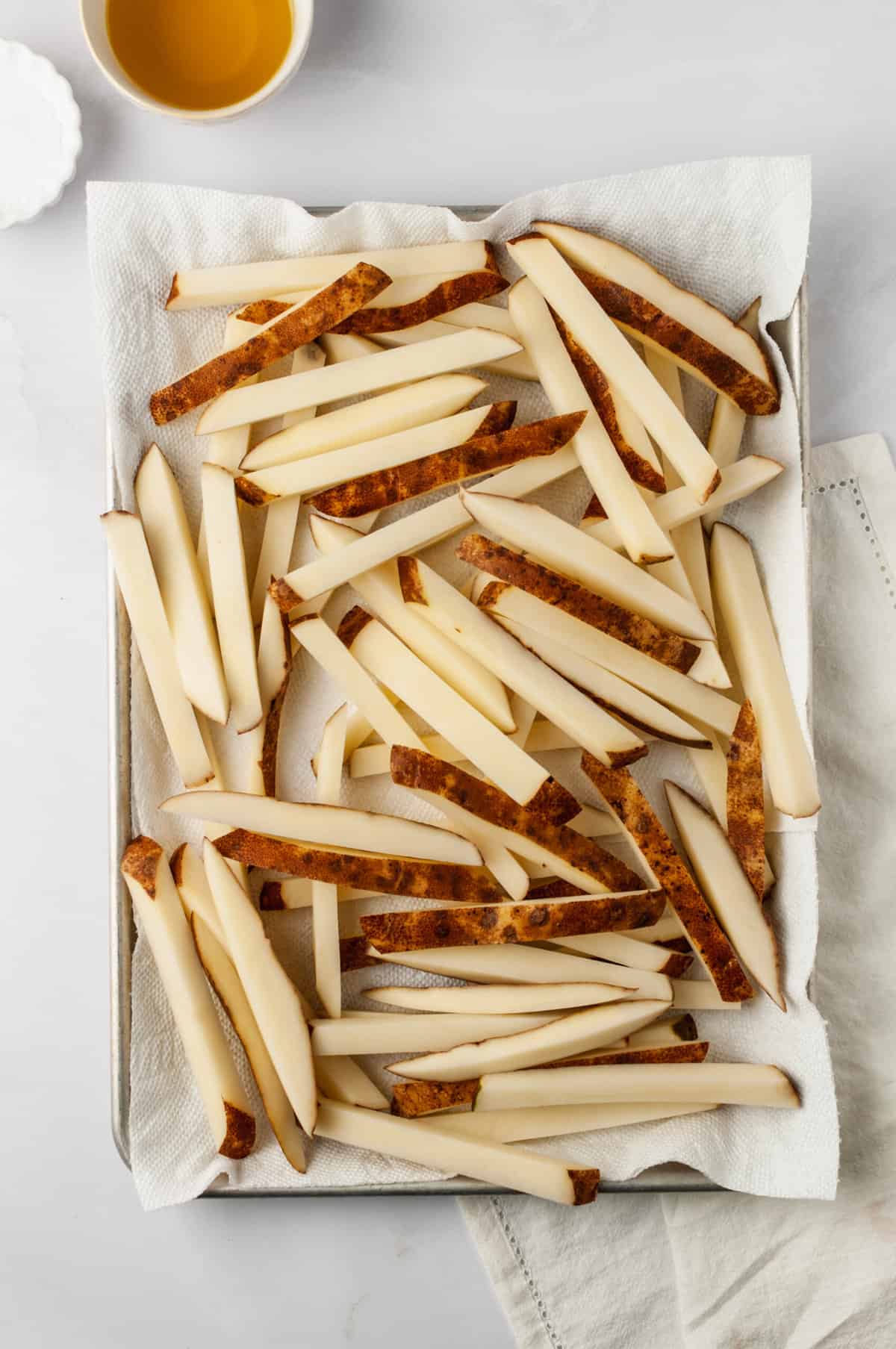 Overhead view of soaked potatoes draining on paper towel