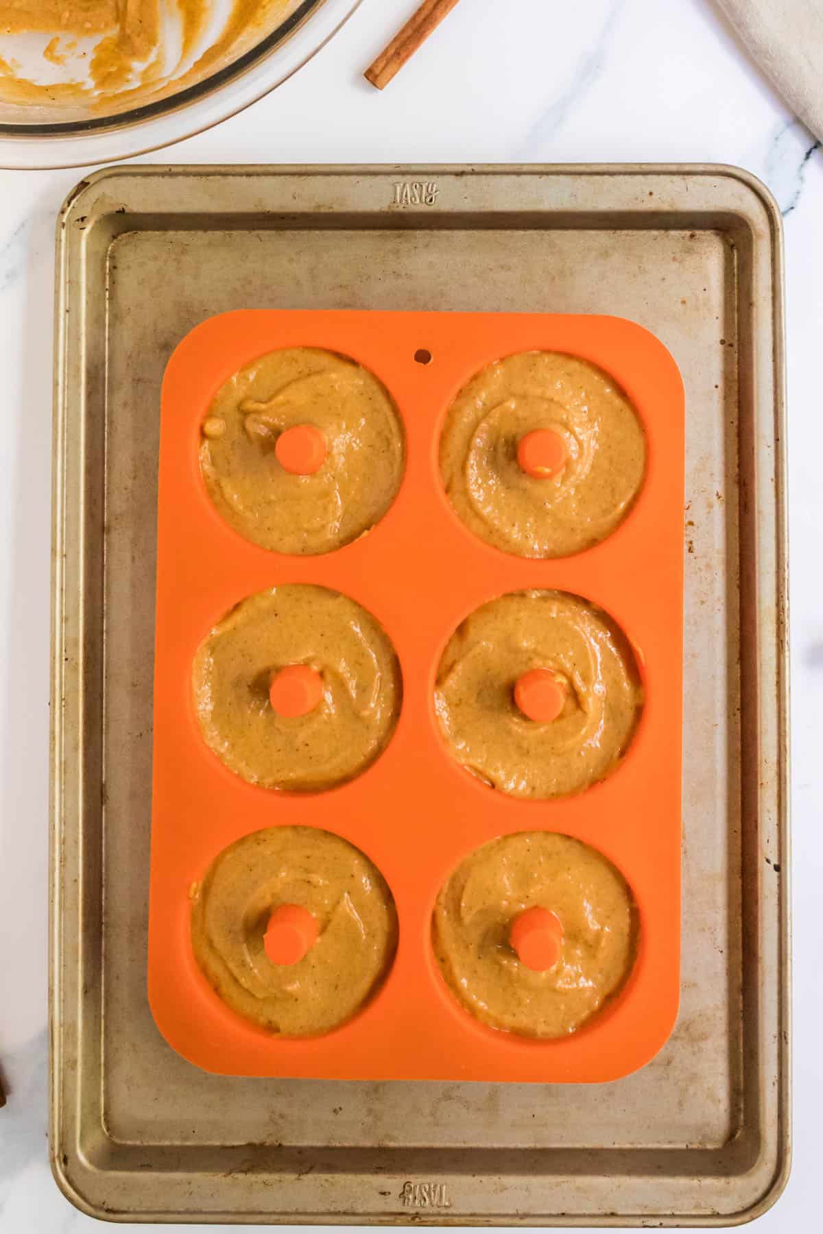 Pumpkin donut batter in a silicon baking mold.