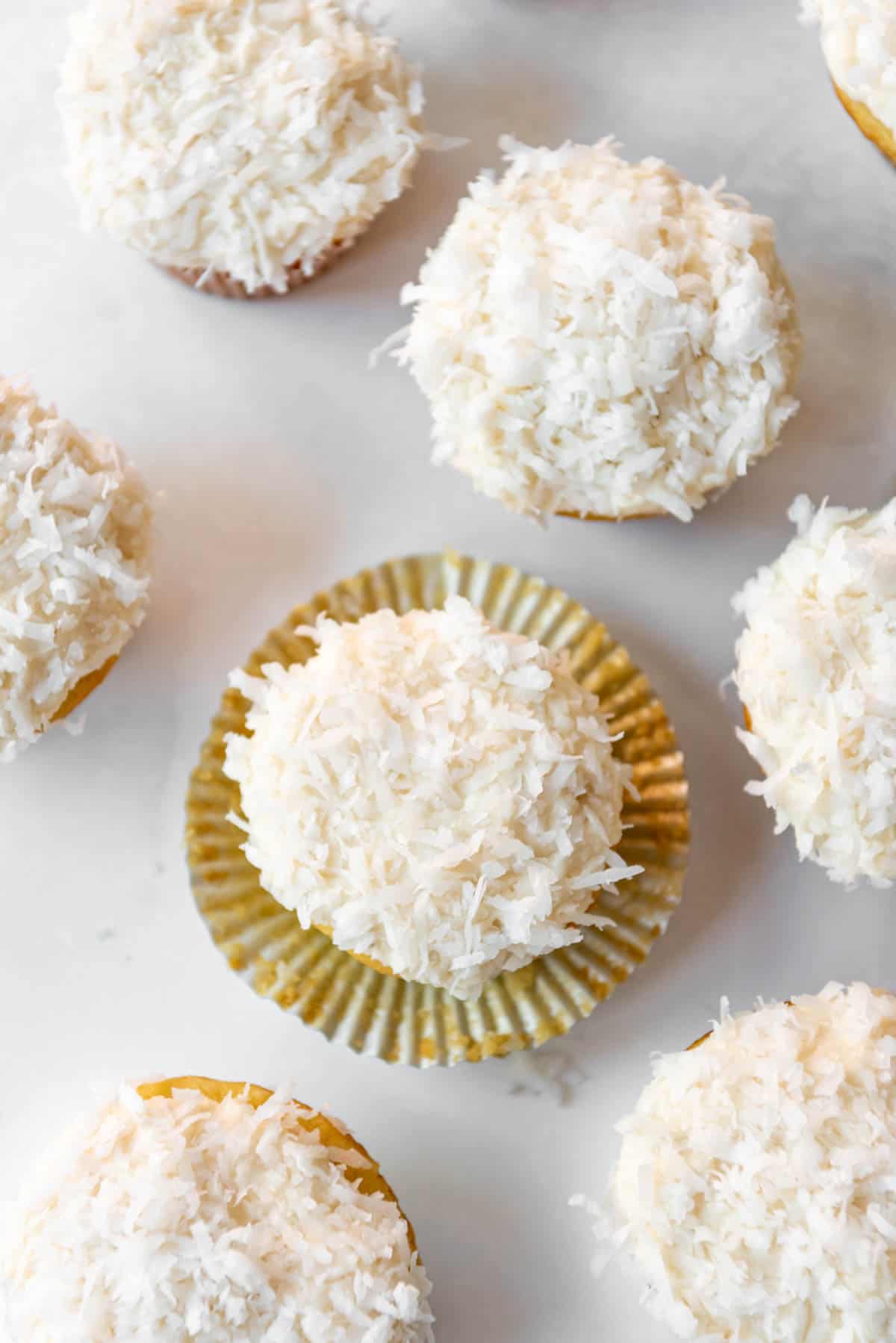 An overhead image of cupcakes topped with sweetened shredded coconut.