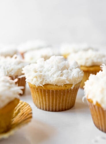 Homemade coconut cupcakes topped with sweetened shredded coconut.