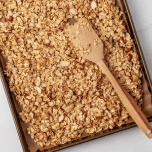 Easy homemade granola on a baking sheet with a spatula.
