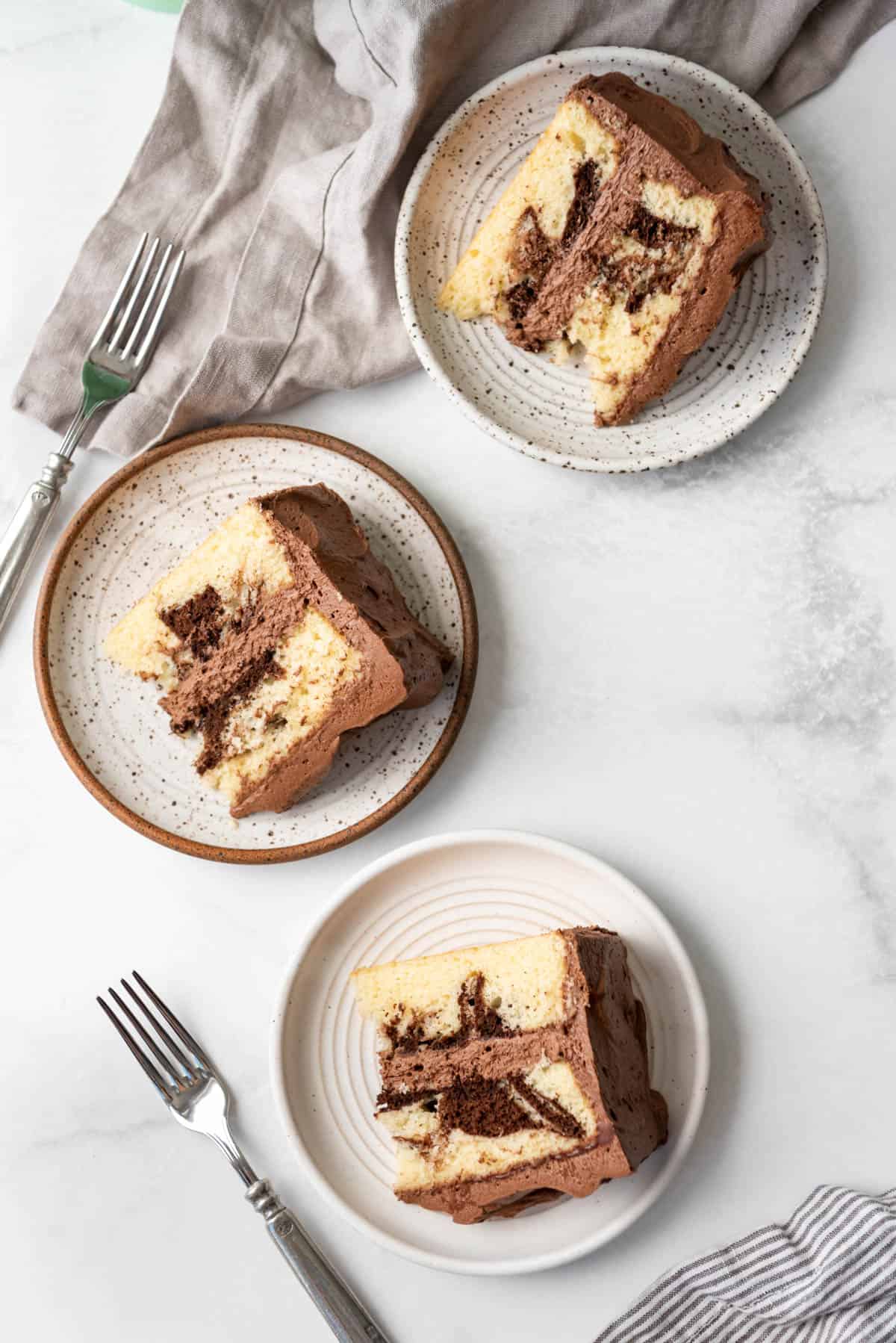 Three slices of marble cake on plates.