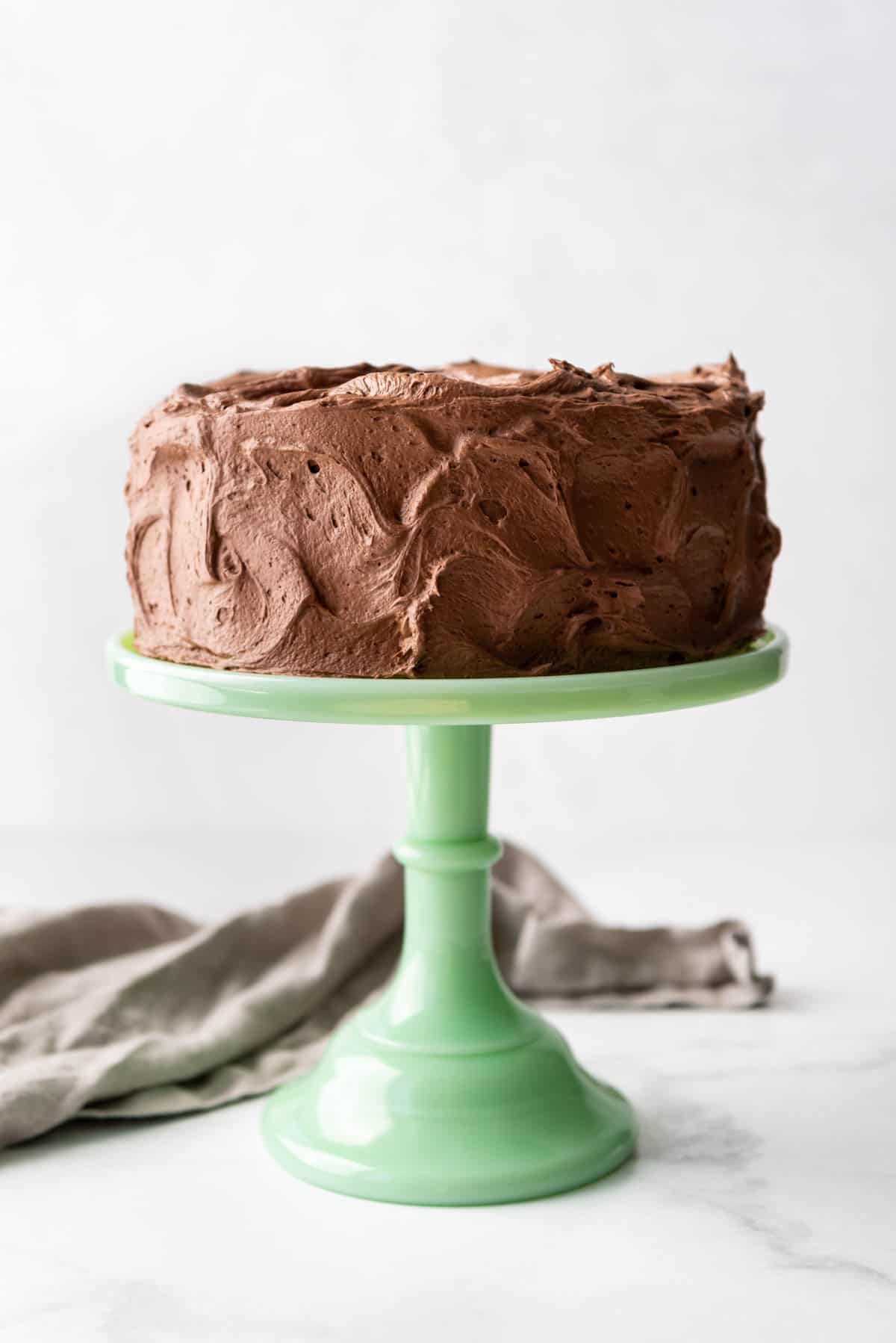 A chocolate frosted marble cake on a green cake stand.