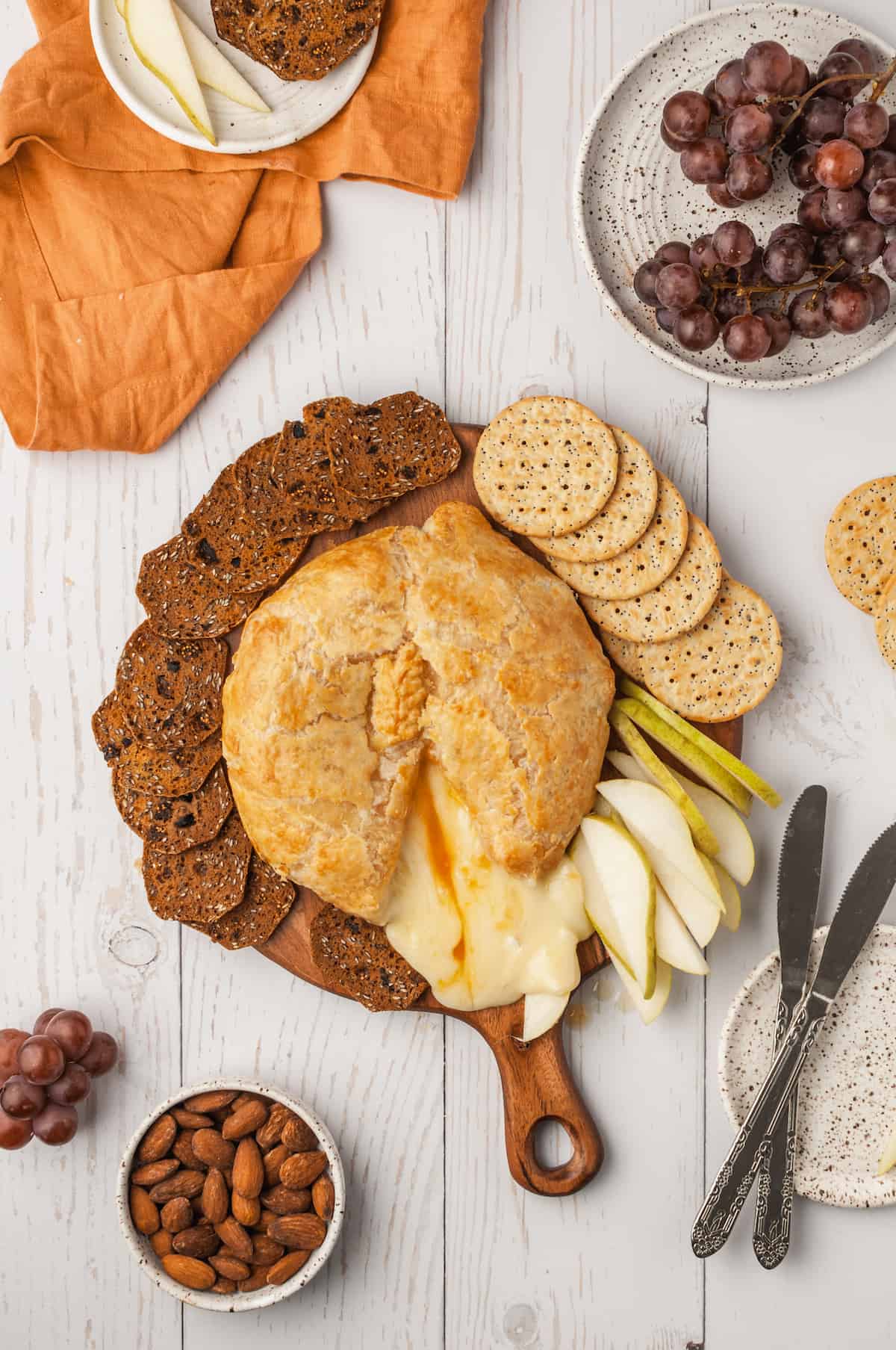 Overhead view of baked brie on board with sliced pears and crackers