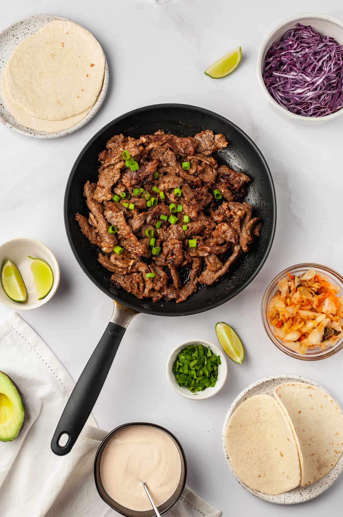 Overhead view of bulgogi in skillet with other taco components
