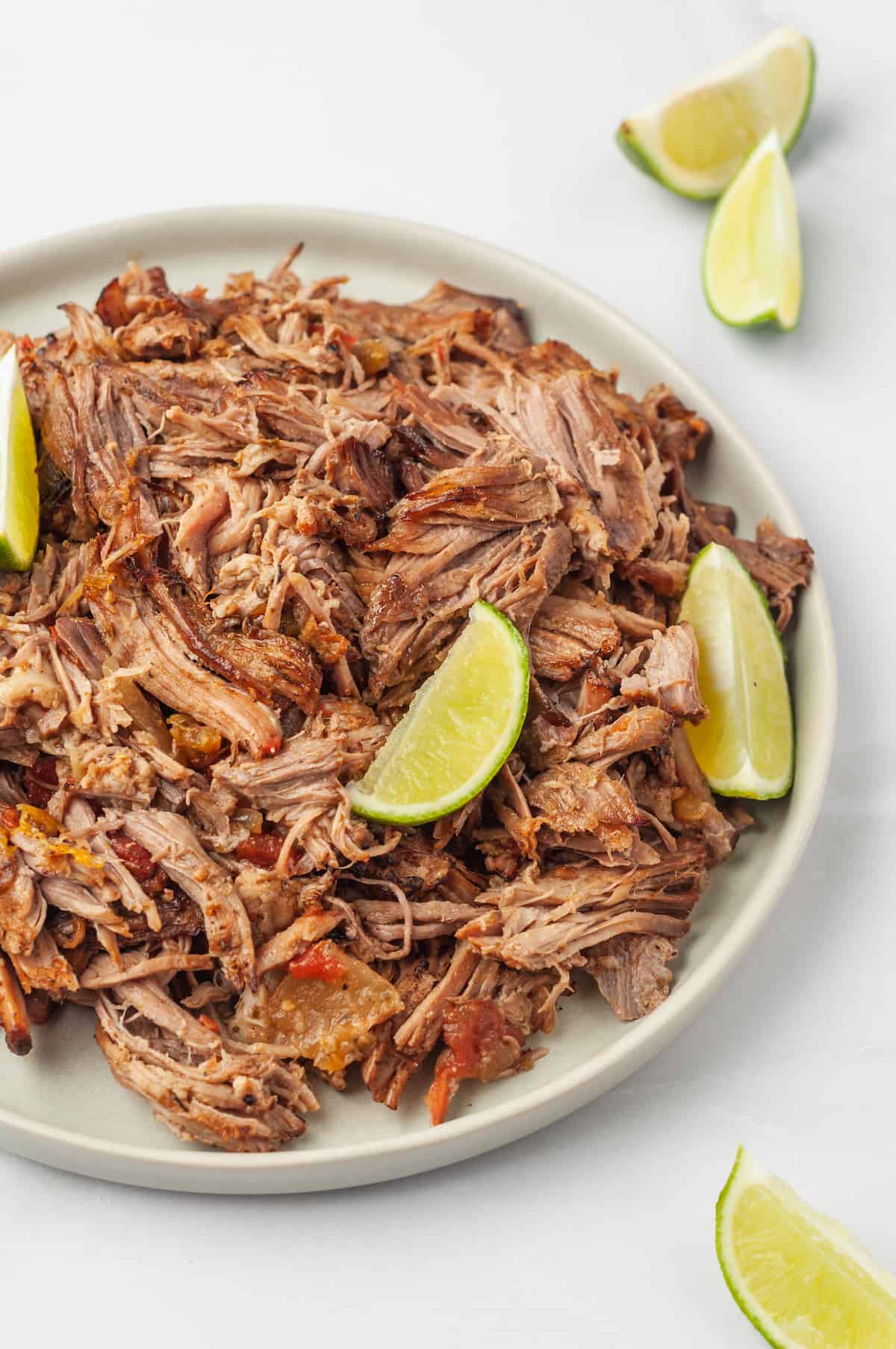 Plate of pork carnitas with lime wedges