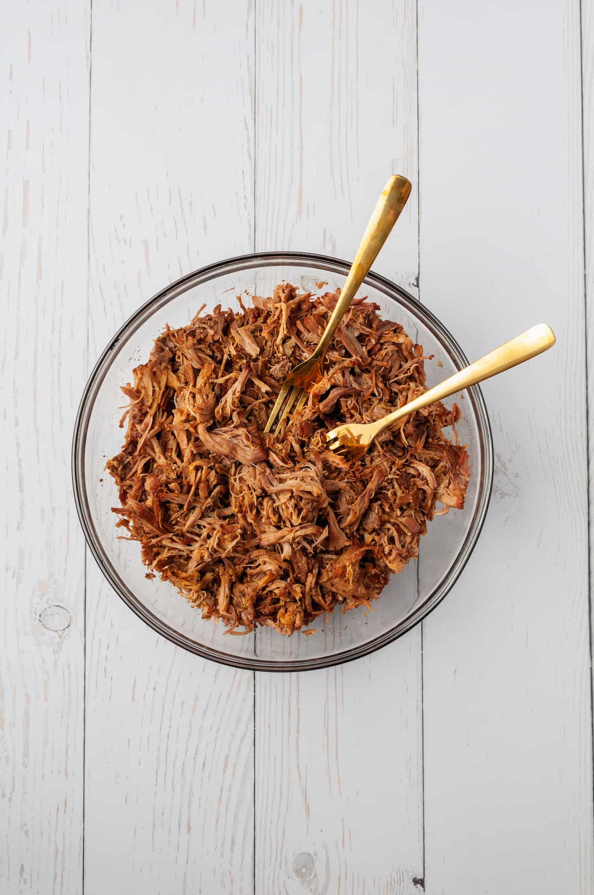 Overhead view showing two forks in bowl of shredded pork
