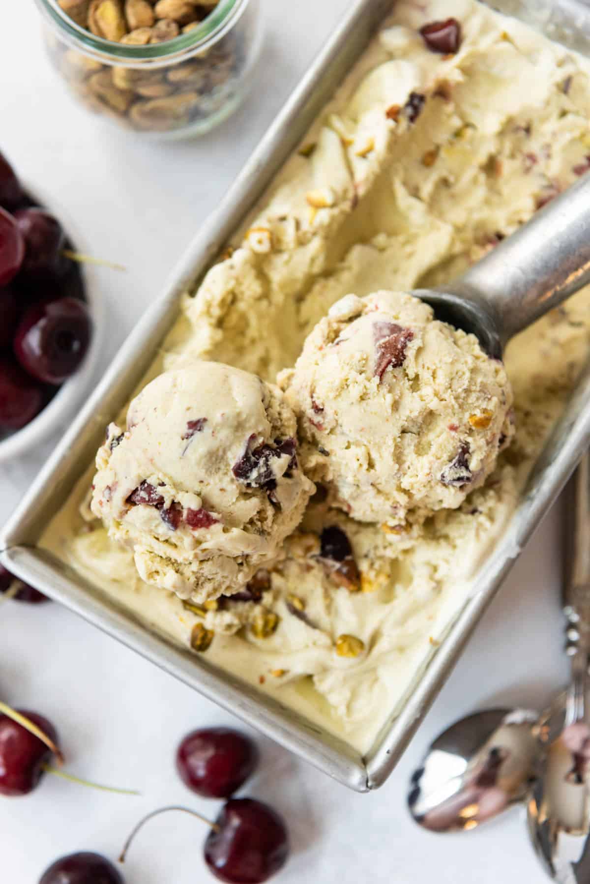 An overhead image of scoops of cherry pistachio ice cream on top of the rest of the ice cream in a pan.