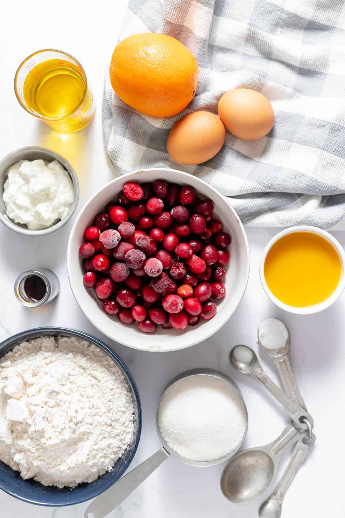 Ingredients for cranberry orange muffins in separate bowls.