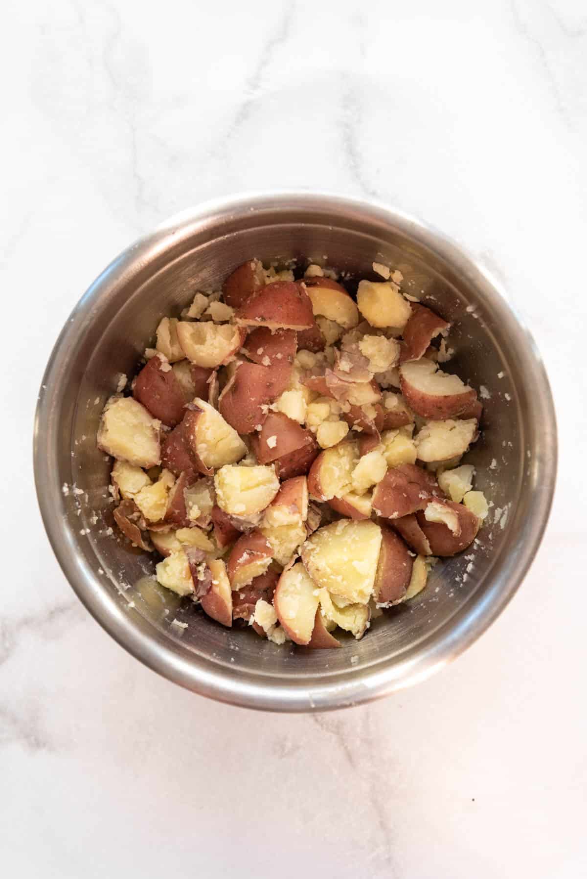 Cooked red potatoes with skins on in a large mixing bowl.
