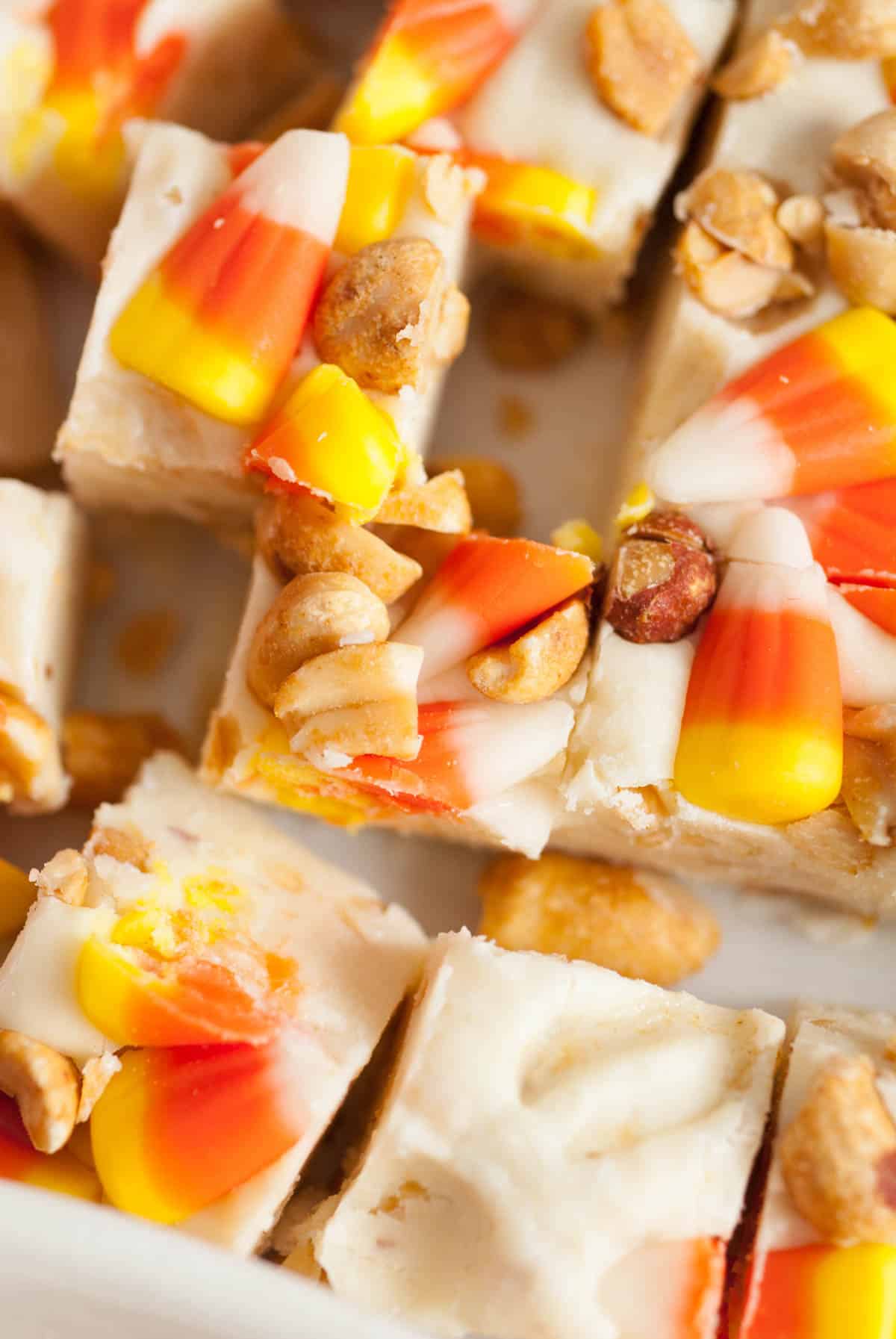 Pieces of candy corn and salted roasted peanuts on top of creamy fudge squares.