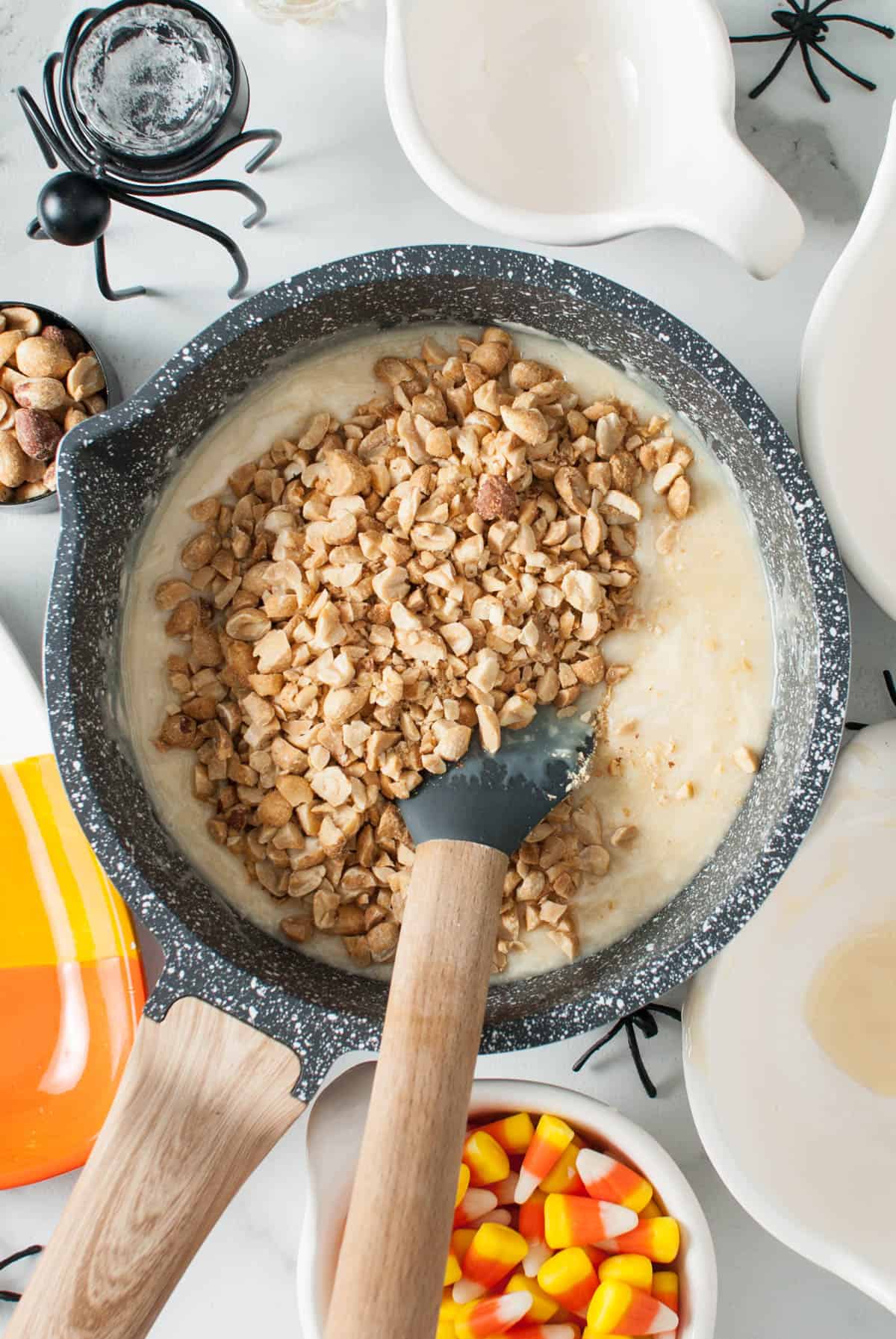 Adding chopped dry roasted peanuts to a pan of white chocolate fudge.