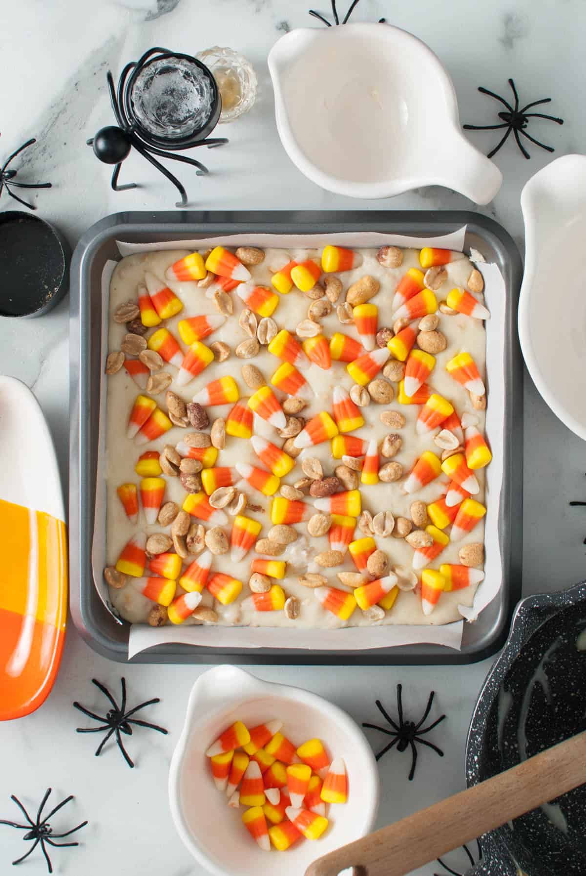 A batch of creamy white chocolate fudge with candy corn and dry roasted peanuts sprinkled on top.