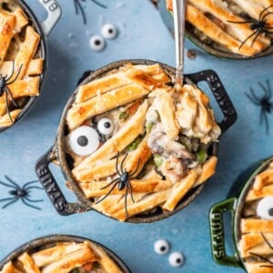Individual mummy chicken pot pies with eyeball sprinkles with a spoon lifting a bite out of one of them.