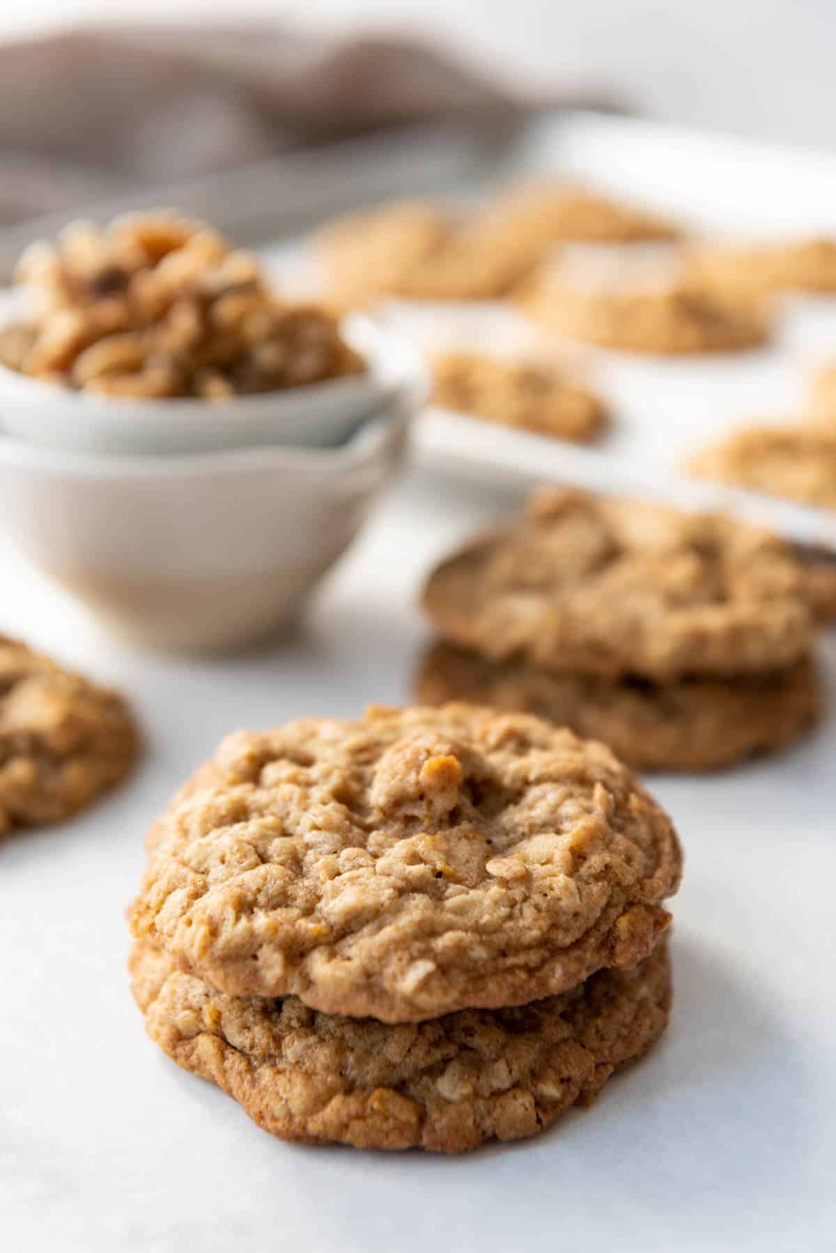 Old-fashioned ranger cookies in a stack in front of a bowl of walnuts.